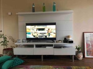 una sala de estar con TV en un centro de entretenimiento blanco en Departamento frente al Lago en Puerto Varas., en Puerto Varas