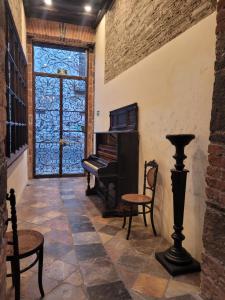 Pokój z pianinem, krzesłami i drzwiami w obiekcie Milo Collection Hotel w mieście Puebla