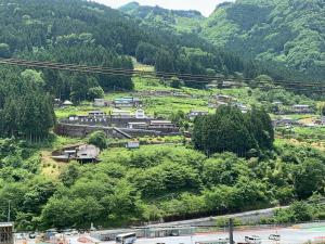 a town on a hill with trees and mountains at Iya Kankou Ryokan in Miyoshi