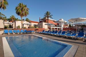 a swimming pool with blue lounge chairs and umbrellas at Caybeach Caleta in Caleta De Fuste