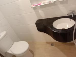 a bathroom with a white toilet and a black sink at APARTEMEN SKY HOUSE BSD in Samporo +8 photos