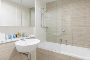 a white bathroom with a sink and a shower at Meriton Suites Herschel Street, Brisbane in Brisbane