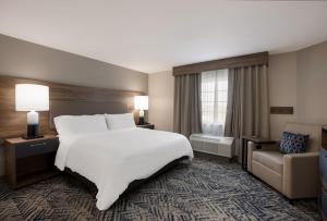 a hotel room with a large white bed and a chair at Candlewood Suites Lafayette - River Ranch, an IHG Hotel in Lafayette