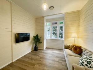 a living room with a couch and a flat screen tv at Taree CBD cottage apartments in Taree