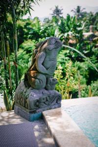 Una statua di una rana che beve da una fontana di Eco Moringa Garden a Banyuwedang