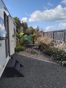 a patio with a table and chairs and flowers at Caravan Glamping Accommodation in Te Awamutu