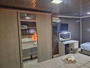 een slaapkamer met een bed, een bureau en een televisie bij Chalé D´Roos III in Canela
