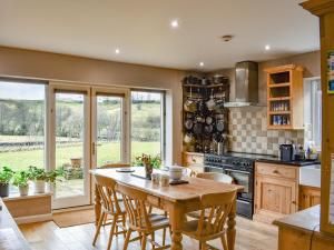 a kitchen with a wooden table and chairs and a stove at Black Bank House in Studdon