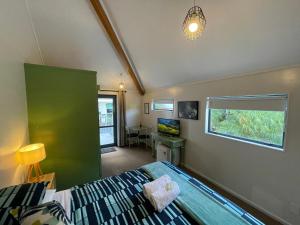a bedroom with a bed and a desk and a window at Peppertree Lodge & Backpackers in Paihia