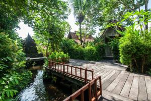 a wooden bridge over a river in a garden at Outpost Ubud Bungalows in Ubud