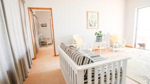 - un lit bébé blanc dans une chambre blanche avec une table dans l'établissement A-View-at-Kingfisher Port Alfred Guest Accommodation, à Port Alfred