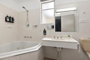 a white bathroom with a tub and a sink at Adelaide Paringa in Adelaide