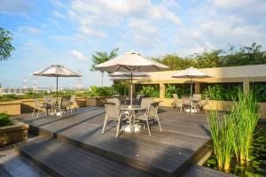 una terraza de madera con mesas, sillas y sombrillas en The Light Hotel Penang en Perai