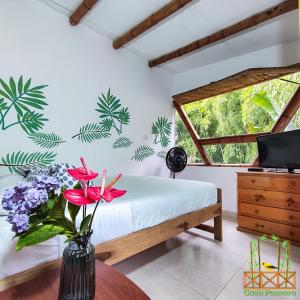 una camera da letto con un letto e un vaso di fiori su un tavolo di Casa Passaro a Calarcá