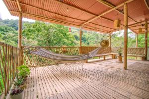 a porch with a hammock on a wooden deck at Paraiso de la sierra in Santa Marta