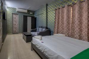 a bedroom with a bed and a chair in it at La Smart Stays in Nāgercoil