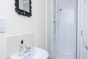 a white bathroom with a sink and a shower at Free Parking Spacious House Near Birmingham in Great Barr