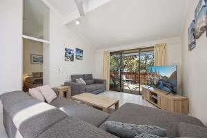 a living room with a couch and a tv at Wolngarin Holiday Resort Noosa in Noosaville