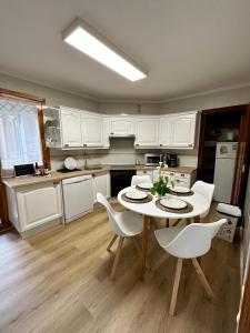 a kitchen with white cabinets and a table and chairs at Villa Yoli, céntrico con plaza de garaje in Avilés