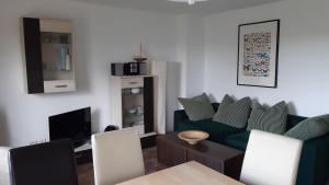 ein Wohnzimmer mit einem grünen Sofa und einem TV in der Unterkunft Ferienhaus Michel in Vorland in Vorland