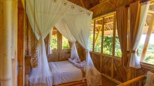 a bedroom with a bed in a room with windows at Elang Hillside Bamboo Villas in Labuan Bajo