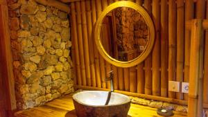 a bathroom with a bath tub with a mirror at Elang Hillside Bamboo Villas in Labuan Bajo