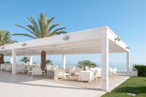 a pavilion with white tables and chairs and the ocean at Hotel Sporting in Casalbordino
