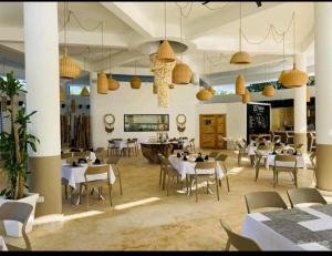 a restaurant with white tables and chairs and pendant lights at LUXURY IN LAS TERRENAS AMARE in Santa Bárbara de Samaná