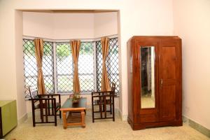 a room with chairs and a wooden cabinet and a window at ATTIMARA HOMESTAY in Somvārpet