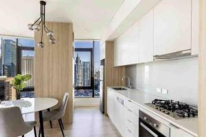 a kitchen with white cabinets and a table and a dining room at Luxury Stay in Sydney CBD in Sydney