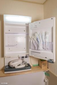 a refrigerator with a phone and utensils on a shelf at Nanei Building - Vacation STAY 03606v in Kagoshima