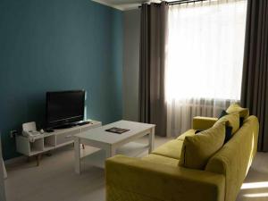 ein Wohnzimmer mit einem gelben Sofa und einem TV in der Unterkunft Comfy apartment in the heart of Ulaanbaatar in Ulaanbaatar