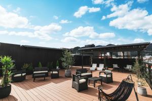 a patio with chairs and tables on a roof at MURE Beppu in Beppu