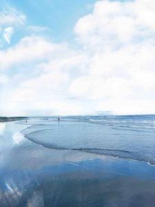 une plage avec des gens qui marchent dans l'eau et les nuages dans l'établissement Beachfront Glamping with Mini Pool Exclusive Property, à Lingayen