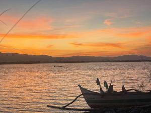 un barco sentado en la orilla de un cuerpo de agua en Beachfront Glamping with Mini Pool Exclusive Property en Lingayen