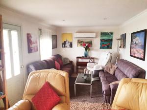 a living room with couches and a table at Daylesford A Very Quiet ABELIA COTTAGE BOTANICAL COTTAGE 10 min walk town in Daylesford