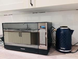 a microwave oven with a tea kettle in a kitchen at Cozzy in London