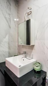een badkamer met een witte wastafel en een spiegel bij Emporis SOHO Kota Damansara by Airhost in Kota Damansara