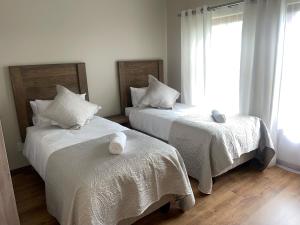 a bedroom with two beds with white sheets and a window at On-Nkwe accommodation in Tierpoort