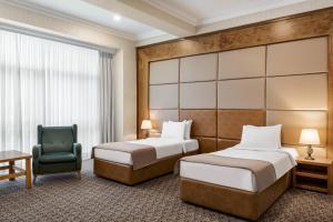 Wyndham Baku في باكو: غرفة فندقية تحتوي على سريرين وكرسي