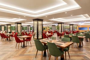 a restaurant with wooden tables and chairs and red chairs at Wyndham Baku in Baku