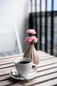 a cup of coffee and a vase with flowers on a table at Native Apartments Barska 69 in Krakow