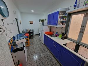 a kitchen with blue cabinets and a white refrigerator at Apartment & Beach breakfast free in Playa del Burrero