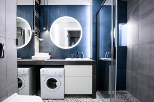 a bathroom with a washer and dryer and a mirror at Native Apartments Barska 69 in Krakow