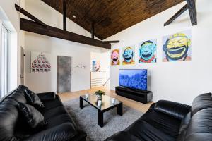 a living room with black leather couches and a flat screen tv at VILLA ROCHALIE by Hakuba Hotel Group in Hakuba