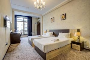 ein Hotelzimmer mit 2 Betten und einem Kronleuchter in der Unterkunft Hotel Touristan Bishkek in Bischkek