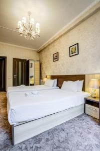 ein Schlafzimmer mit einem großen weißen Bett und einem Kronleuchter in der Unterkunft Hotel Touristan Bishkek in Bischkek