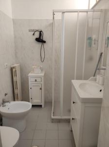 La salle de bains blanche est pourvue d'une douche, de toilettes et d'un lavabo. dans l'établissement ZEUS, à Monopoli