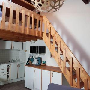 a kitchen with a wooden staircase in a room at Studio maubuisson lac/océan 4/6 personnes in Carcans