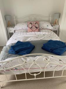 a white bed with two blue towels on it at The Nest at Walnut Cottage in Burrowbridge